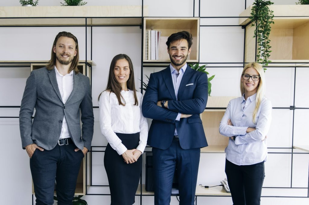 Group of friendly businesspeople in suits standing at office