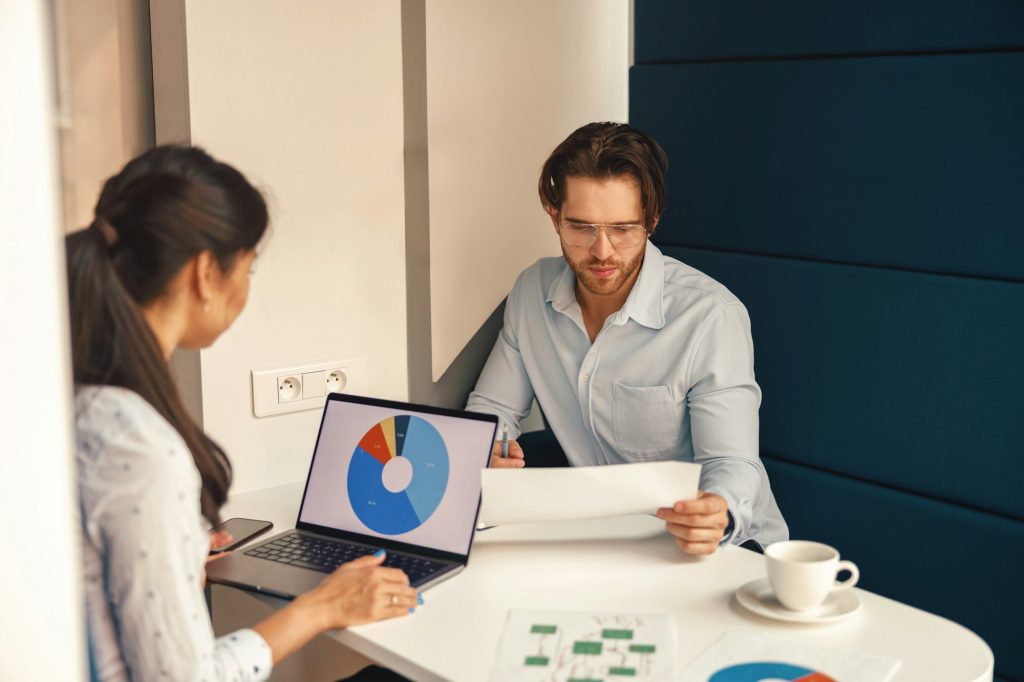 Two business colleagues working together with financial statements in stylish meeting room